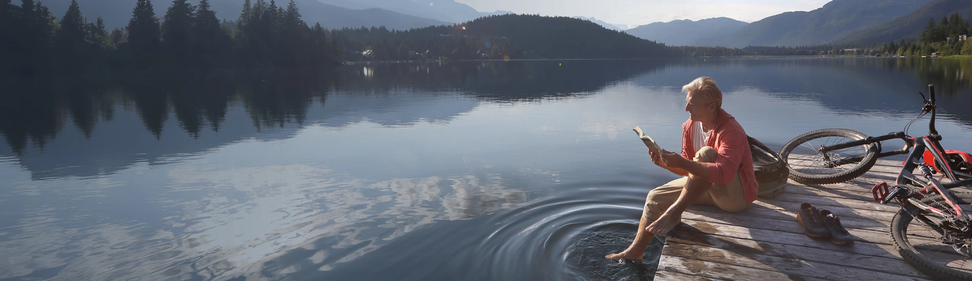 man on a dock on the lake reading a book